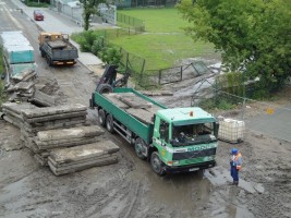 Volvo i Kamaz zabierają tymczasowe płyty betonowe służące jako utwardzenie placu budowy. W oddali zejście do tunelu d...